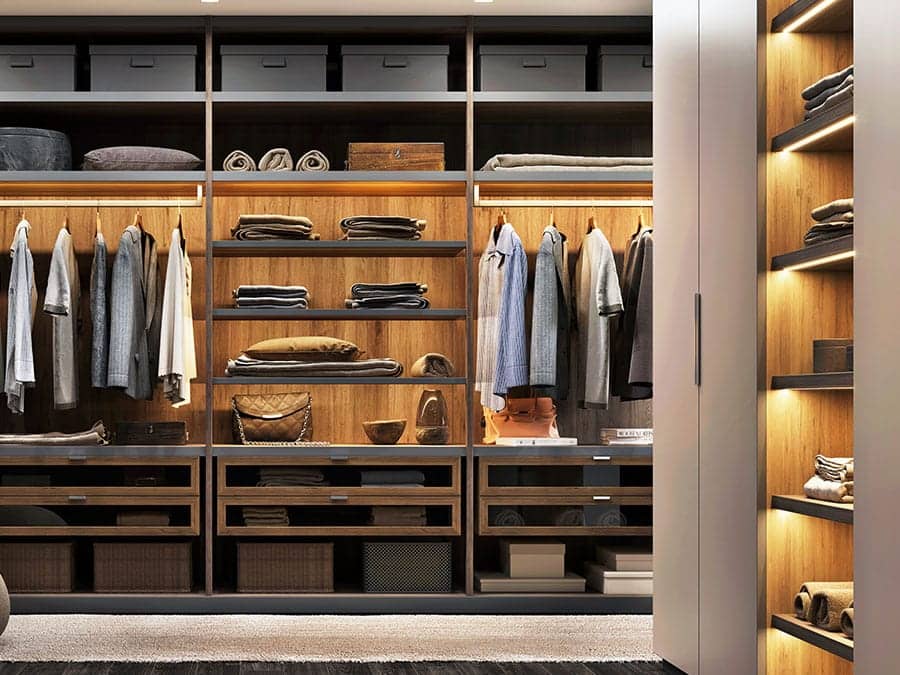 Dressing lumineux avec penderies, étagères en bois, tiroirs vitrés et vêtements rangés