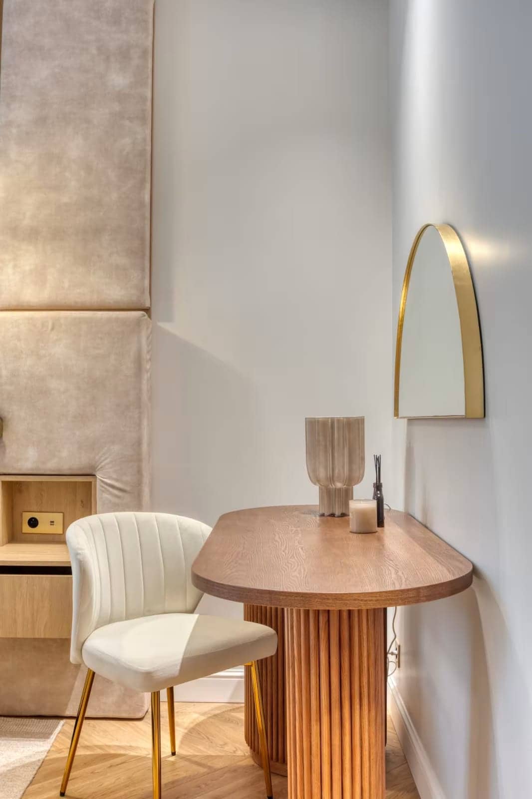 Coin coiffeuse avec table ovale en bois cannelé, chaise crème et miroir en arche doré