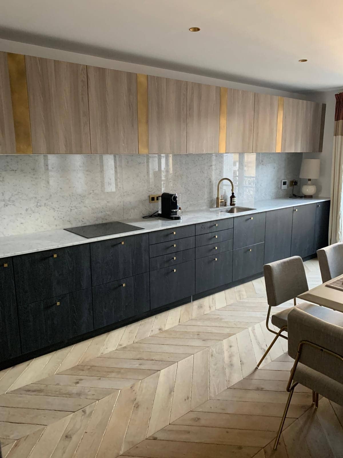 Cuisine linéaire à façades en chêne noirci, hauts en bois et laiton, crédence en marbre