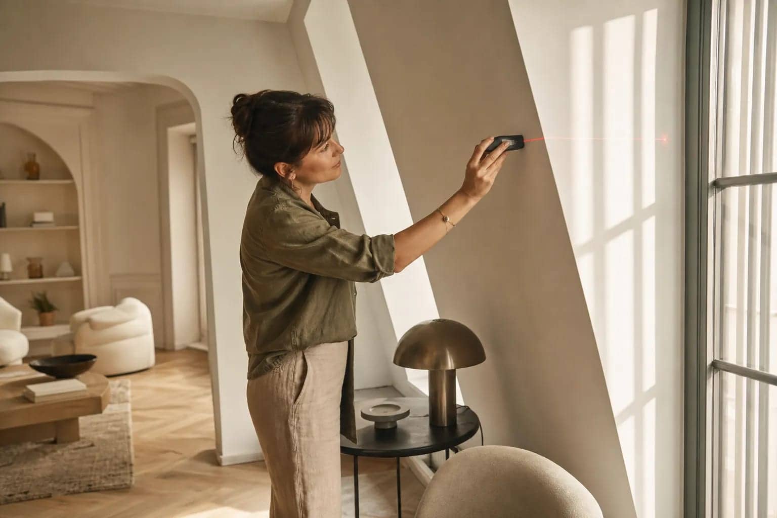Consultante en agencement intérieur appartement paris utilisant un laser pour mesurer une façade intérieure lumineuse et moderne.