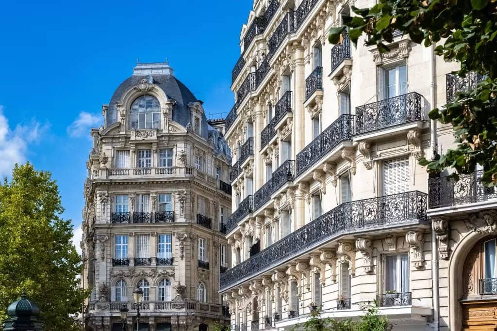 Façades d'immeubles haussmanniens en pierre avec balcons en fer forgé et ciel bleu
