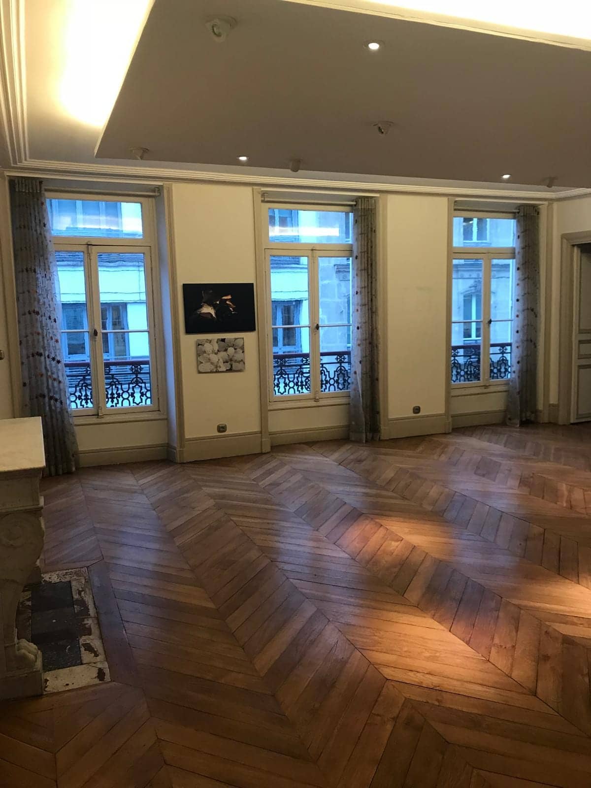 Salon haussmannien avant travaux avec parquet en point de Hongrie, plafond suspendu et cheminée en marbre