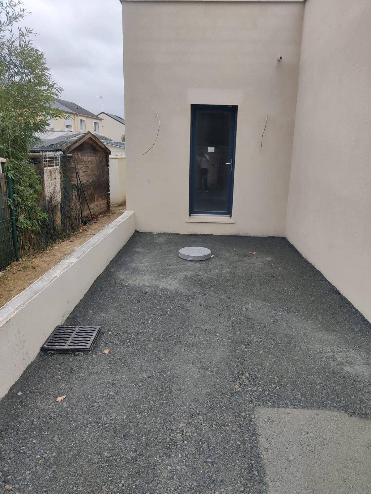 Maison individuelle neuve avec façade enduite beige, porte-fenêtre bleu foncé et cour en gravier