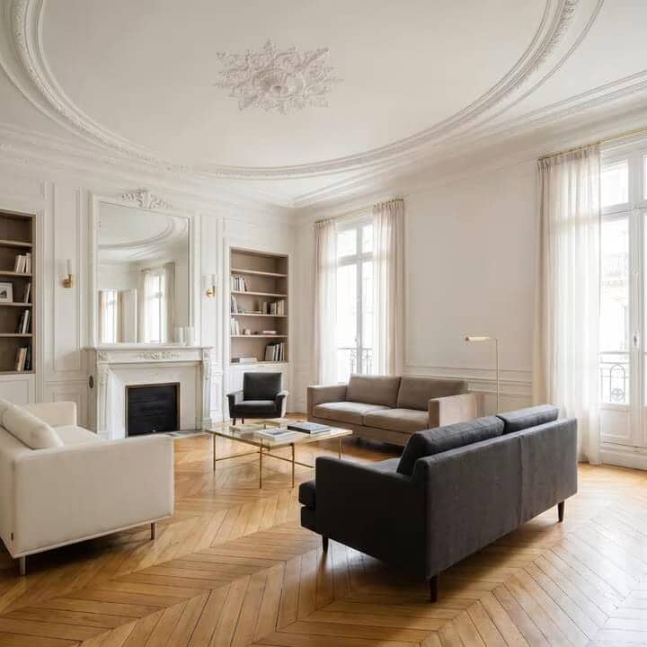Salon haussmannien avec cheminée, moulures, bibliothèques encastrées, canapés et parquet en point de Hongrie