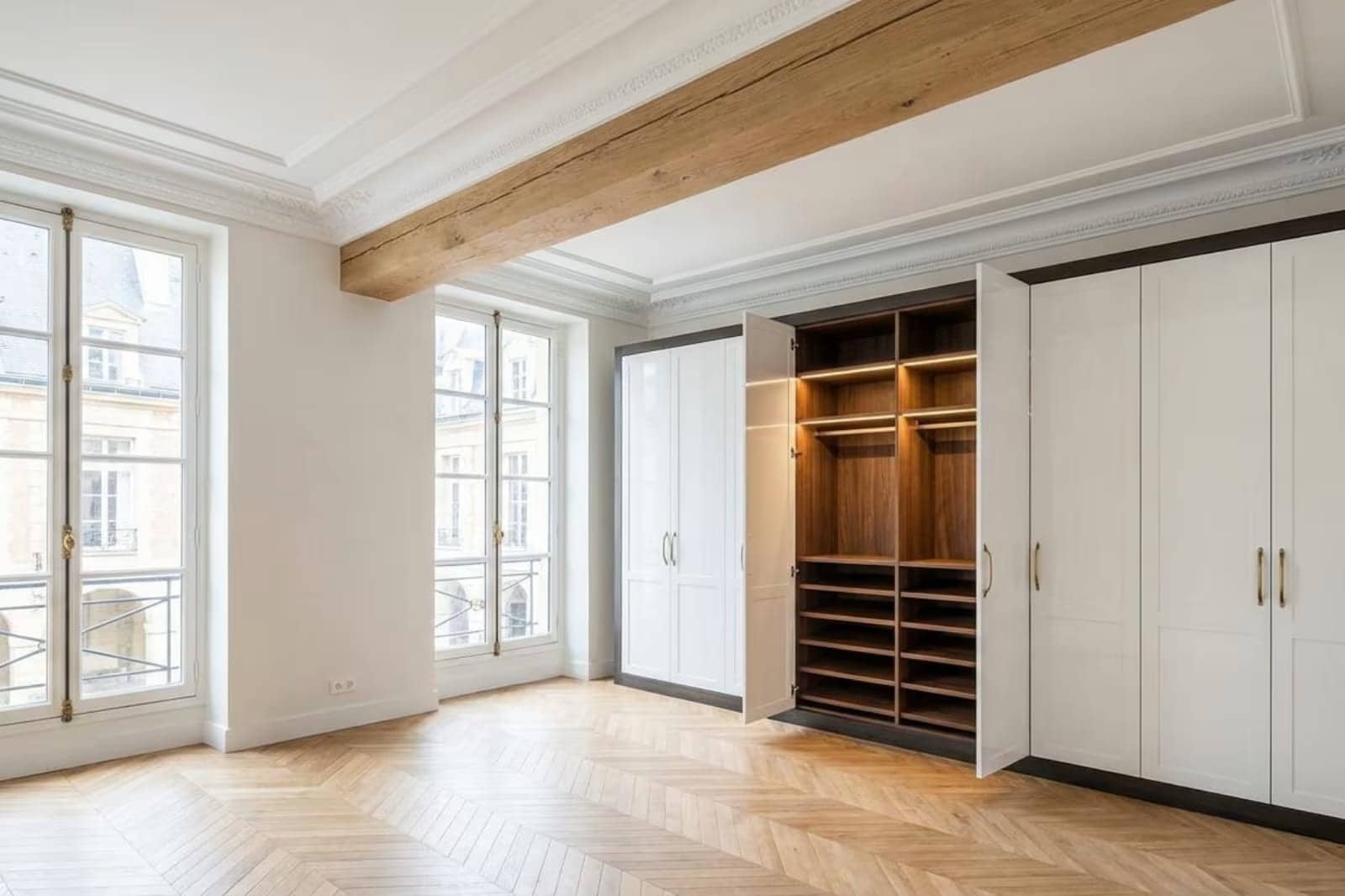 Grand placard blanc ouvert sur dressing en noyer, poutre apparente et parquet en point de Hongrie
