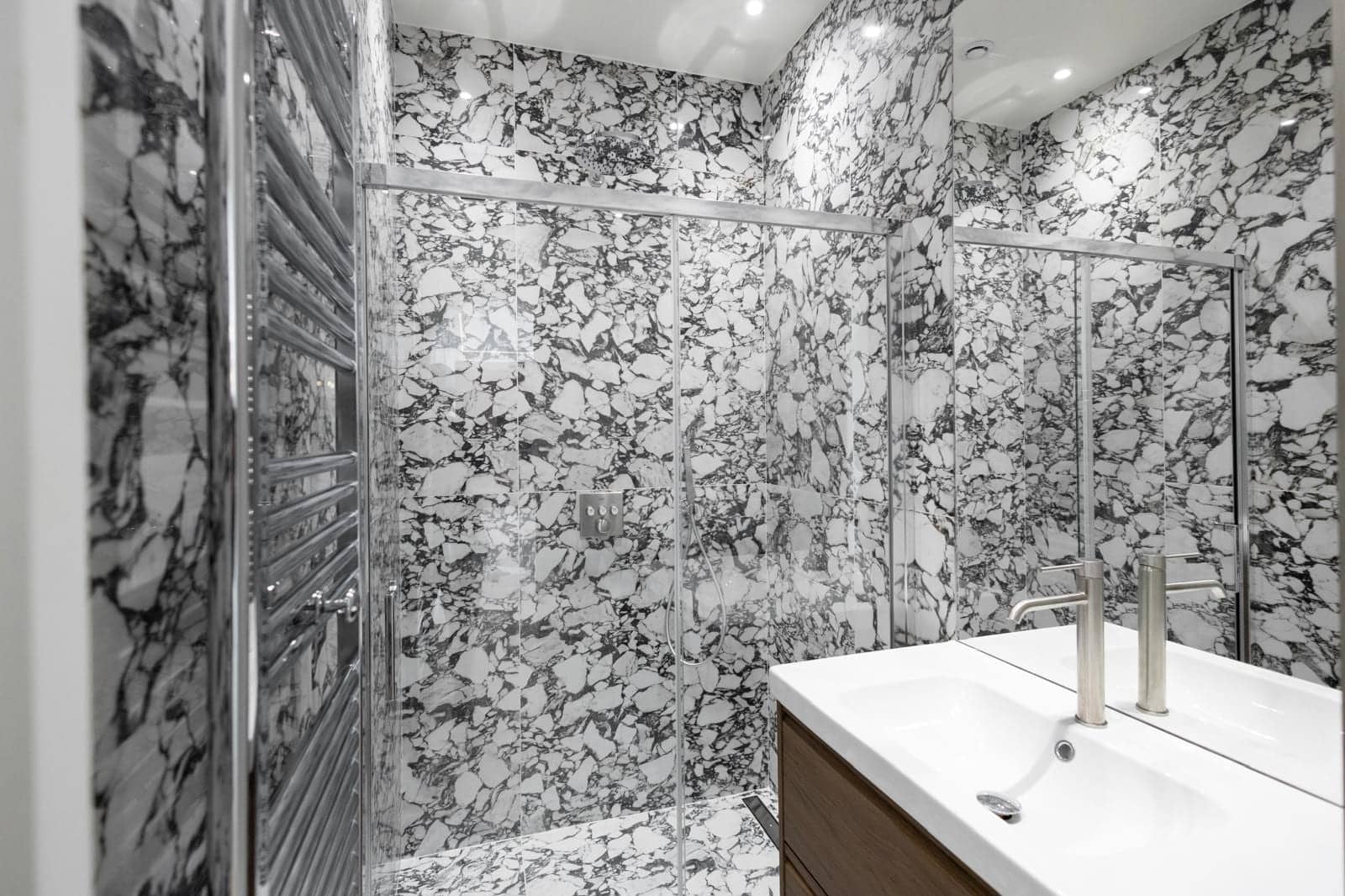 Salle d'eau en marbre noir et blanc avec douche vitrée et meuble vasque en bois à Versailles