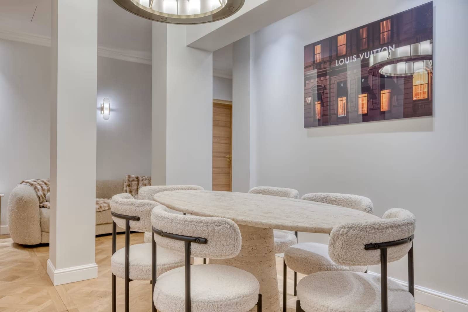 Salle à manger avec table ovale en travertin, chaises en bouclé blanc et parquet