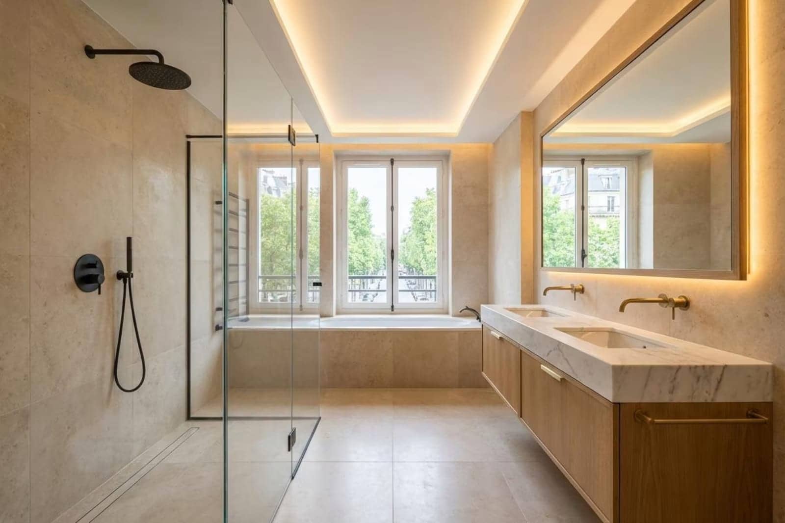 Salle de bain beige avec douche vitrée, baignoire, double vasque en marbre et miroir lumineux, Levallois-Perret