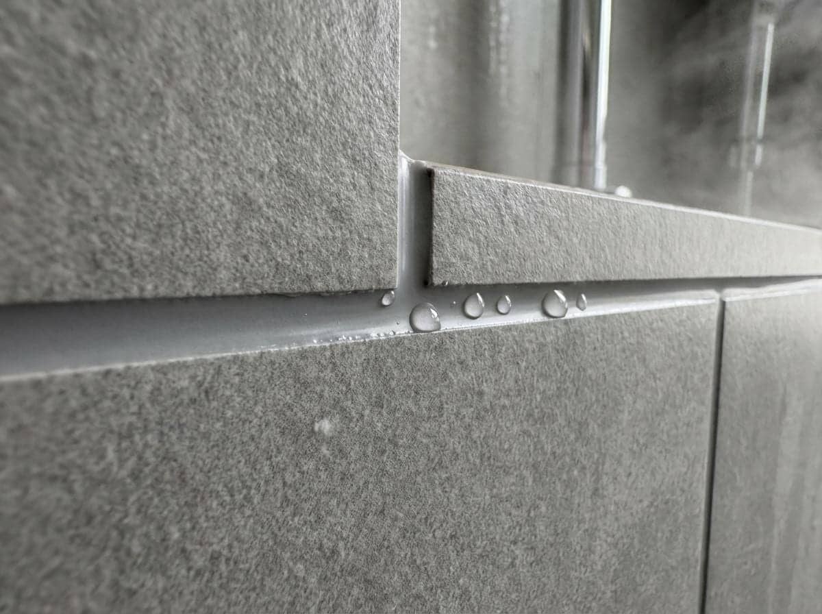 Gros plan sur un joint d'étanchéité entre carreaux gris texturés avec gouttes d'eau à Levallois
