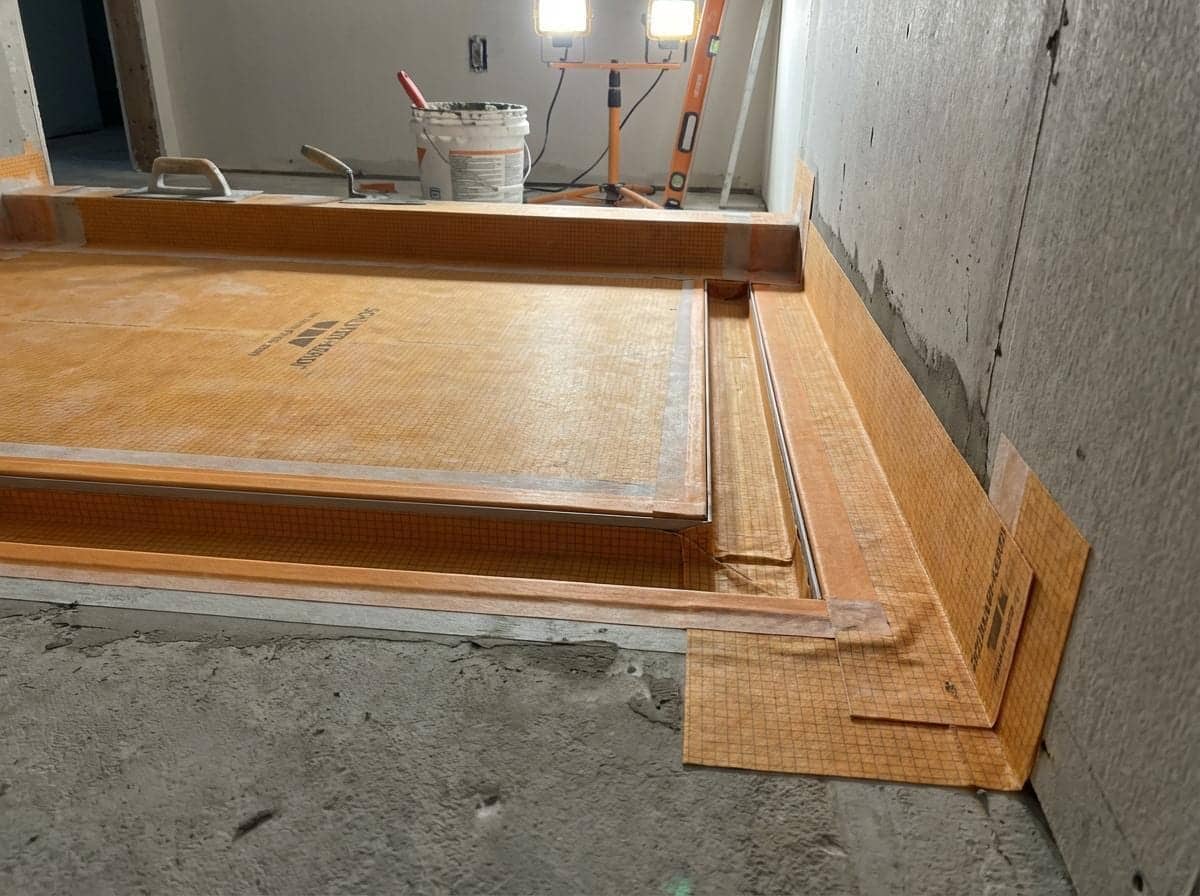 Membrane d'étanchéité orange posée sur le sol et les murs d'une future douche en chantier