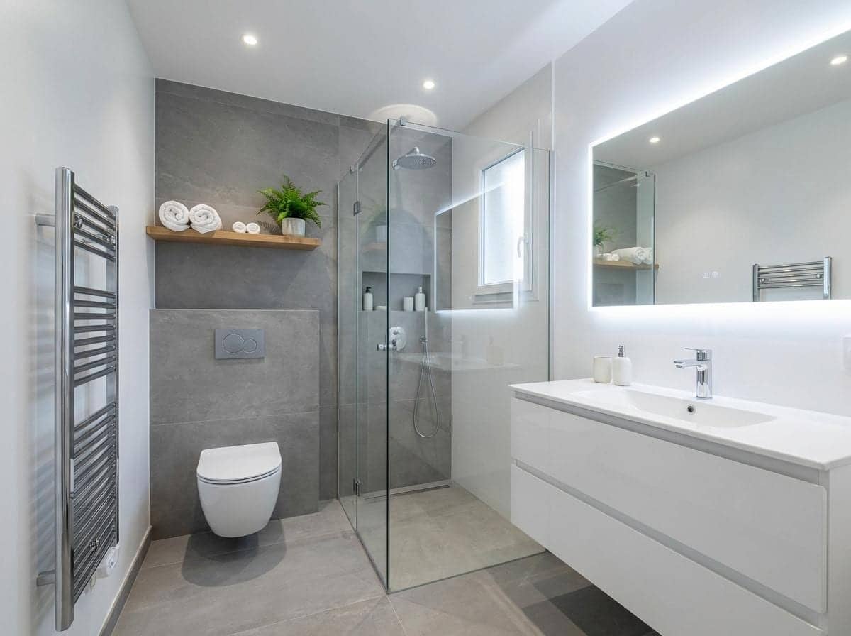 Salle d'eau grise avec douche vitrée, WC suspendu et miroir lumineux à Paris 16e