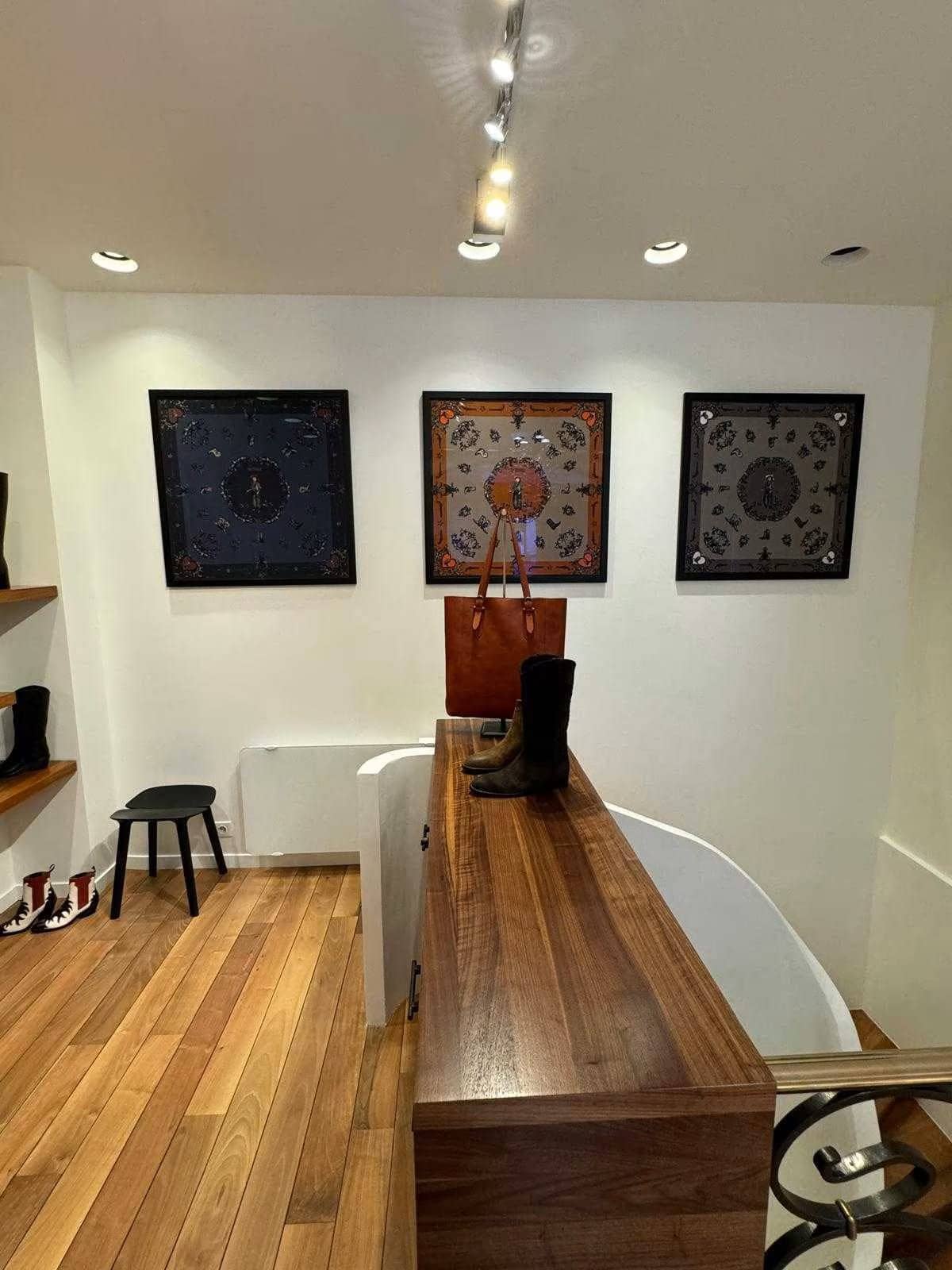 Boutique parisienne avec foulards encadrés, comptoir en noyer, parquet et rampe en fer forgé