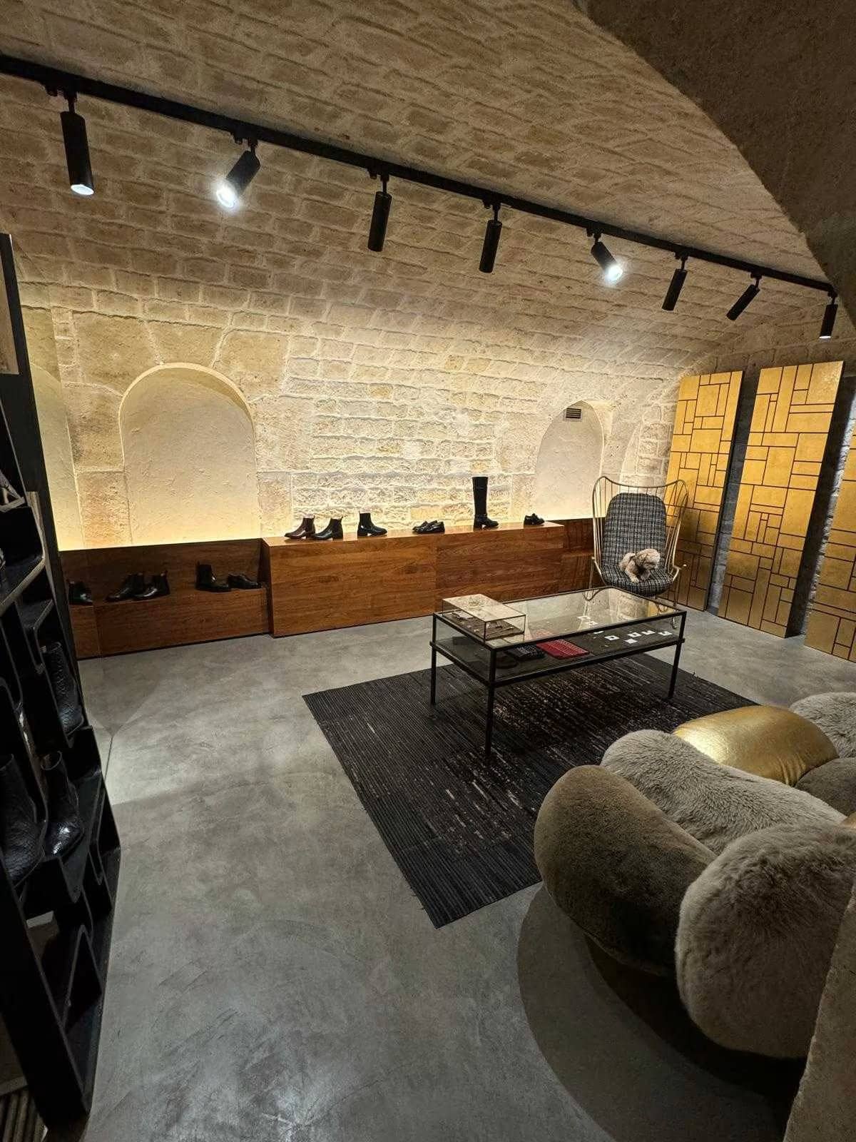 Boutique de chaussures sous voûte en pierre avec spots, présentoirs en bois et table basse à Paris