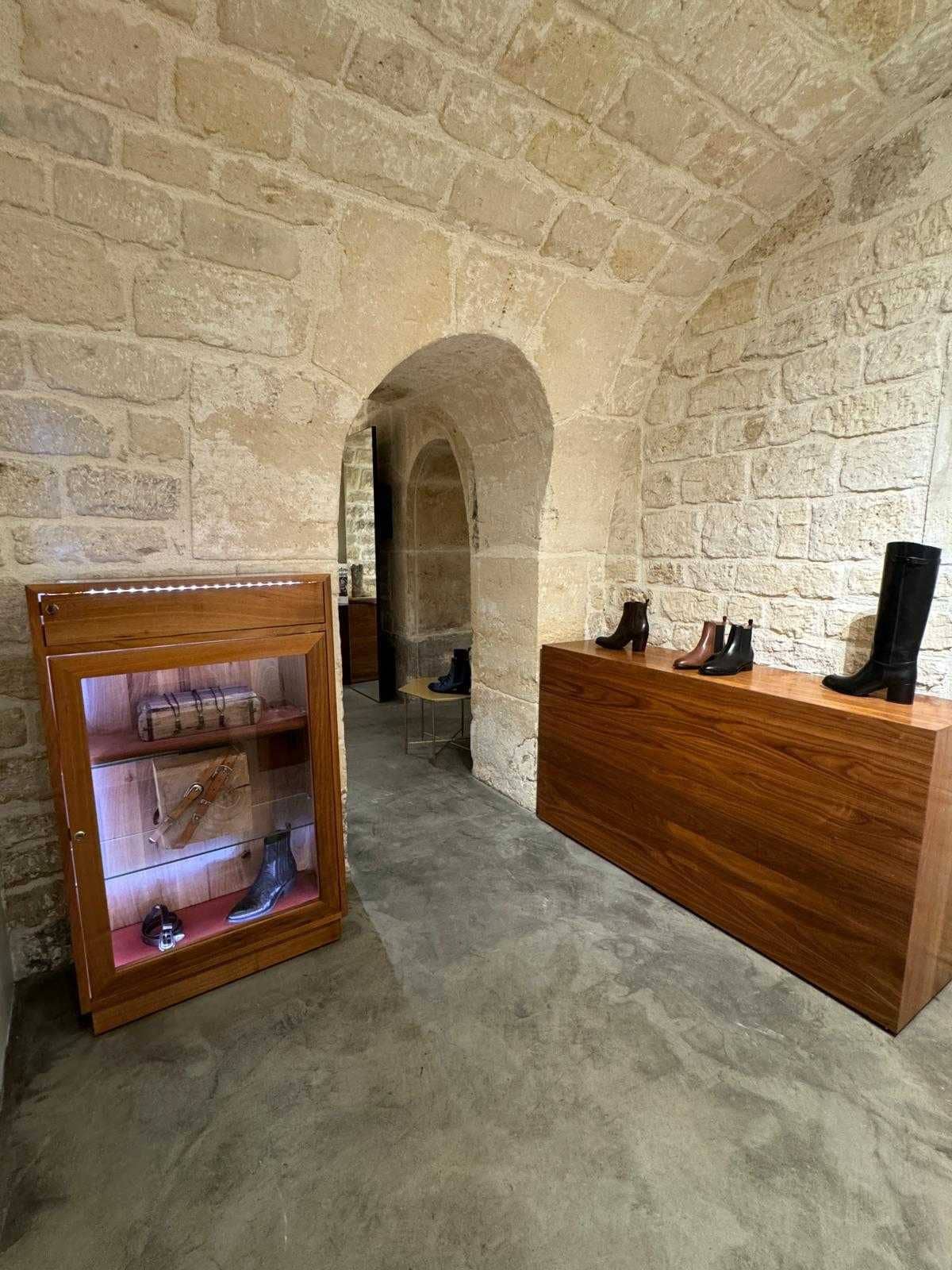 Boutique en pierre apparente voûtée avec vitrine en bois, présentoir de bottes, béton ciré
