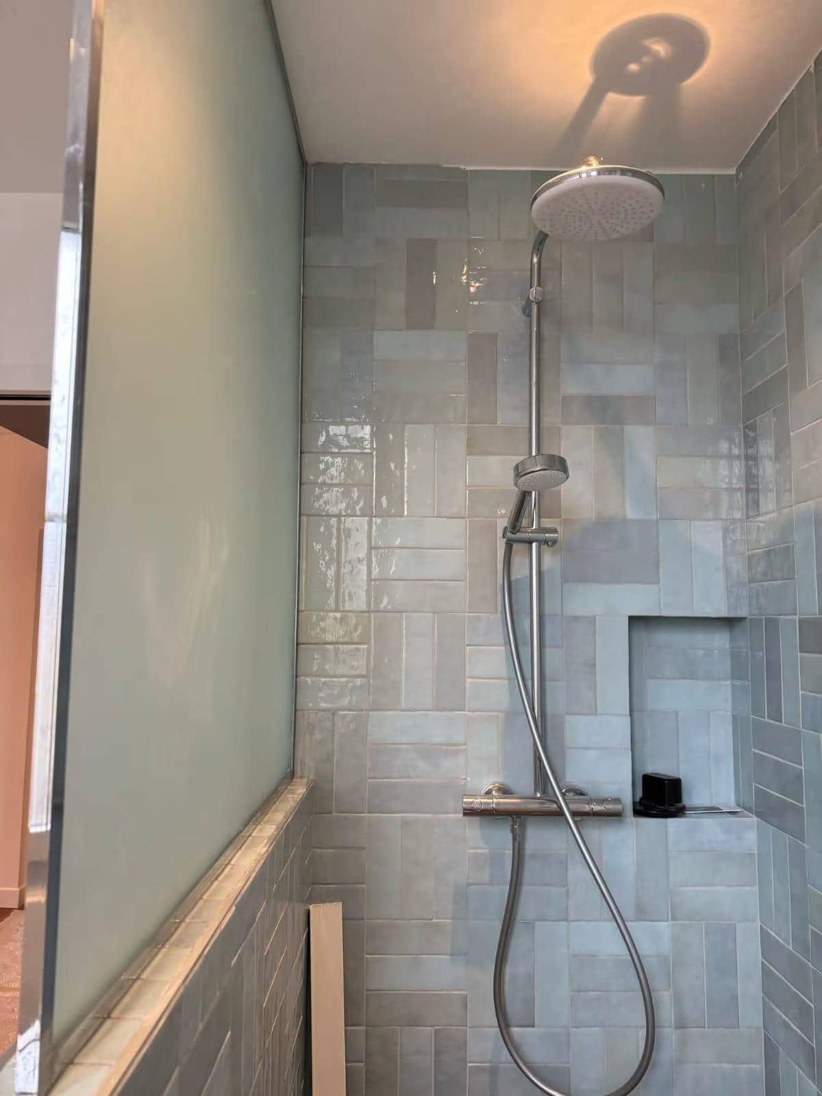 Douche avec faïence zellige bleu-gris posée en appareillage, pomme de douche et niche