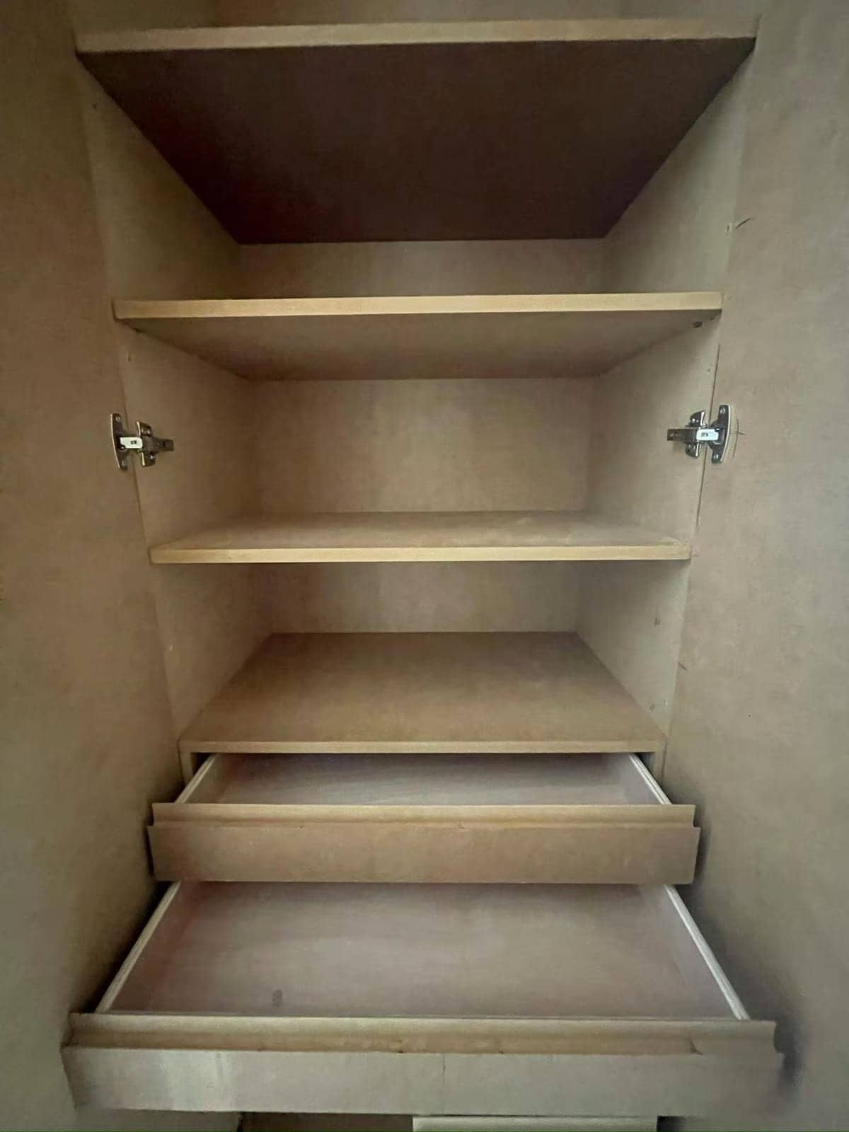 Intérieur d'un placard sur mesure en cours d'agencement avec étagères, charnières et tiroirs