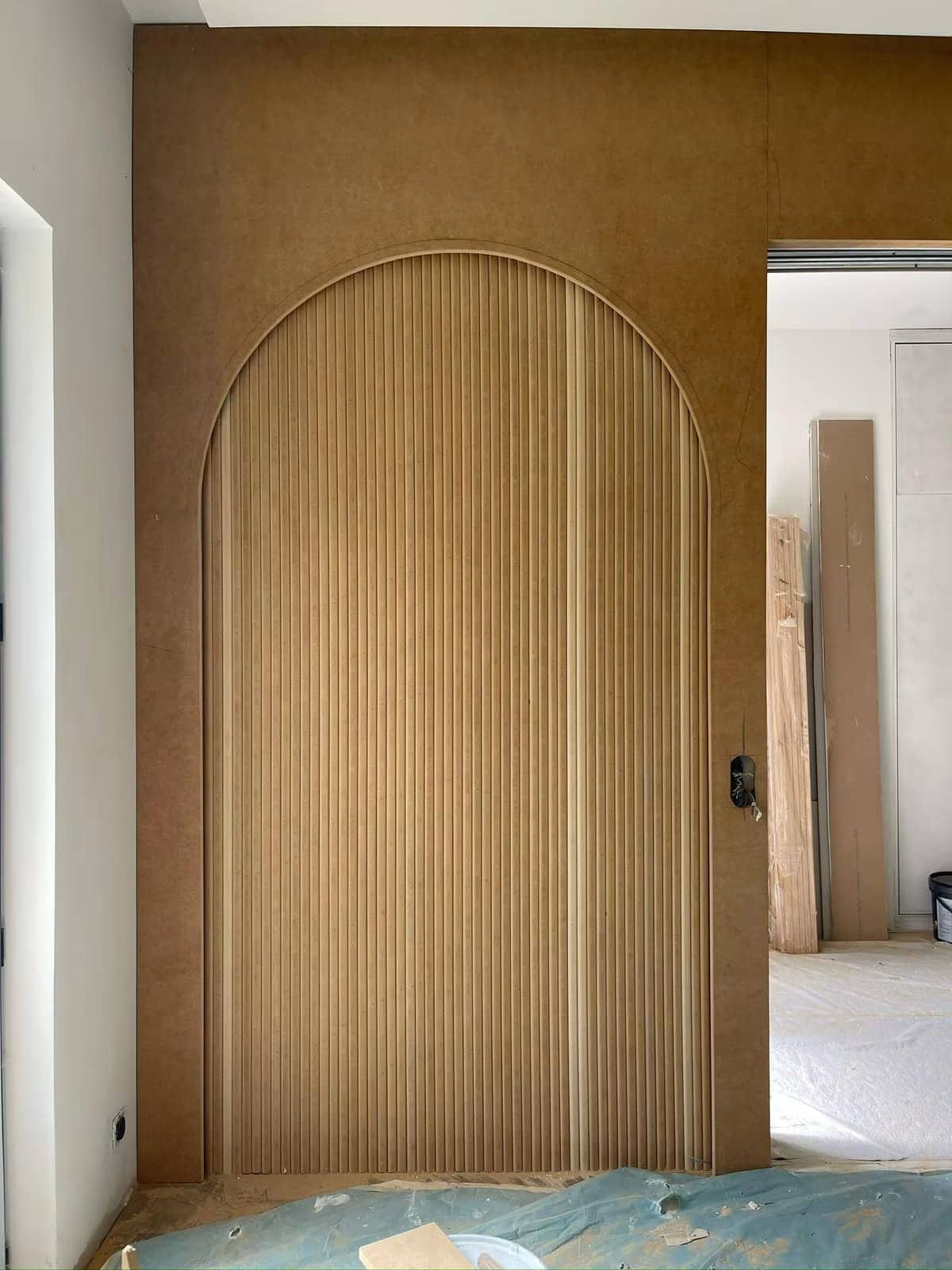 Panneau mural en arche à lames cannelées en MDF brut, menuiserie en cours de chantier