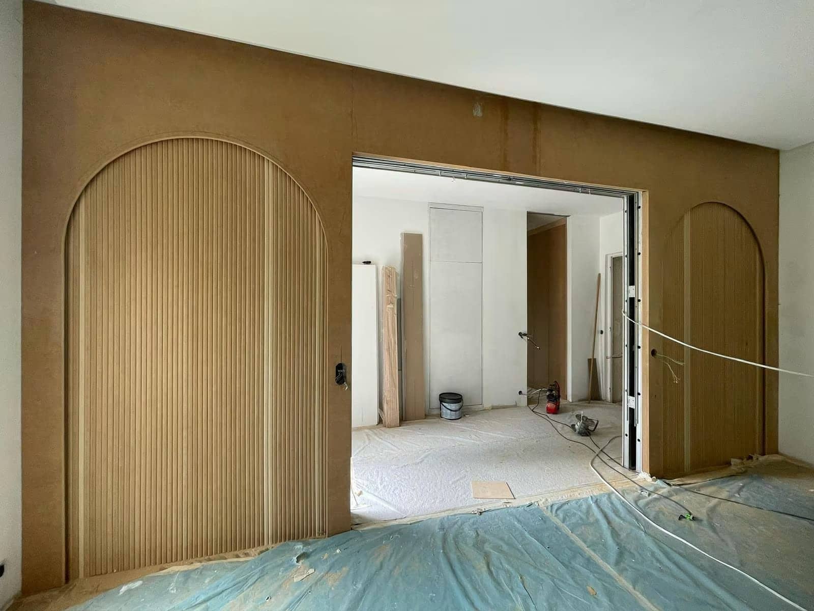 Cloison en MDF avec deux arches cannelées et porte coulissante, en cours de chantier