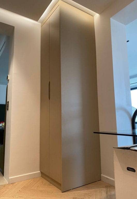 Placard sur mesure beige à portes lisses intégré dans un angle, avec éclairage indirect