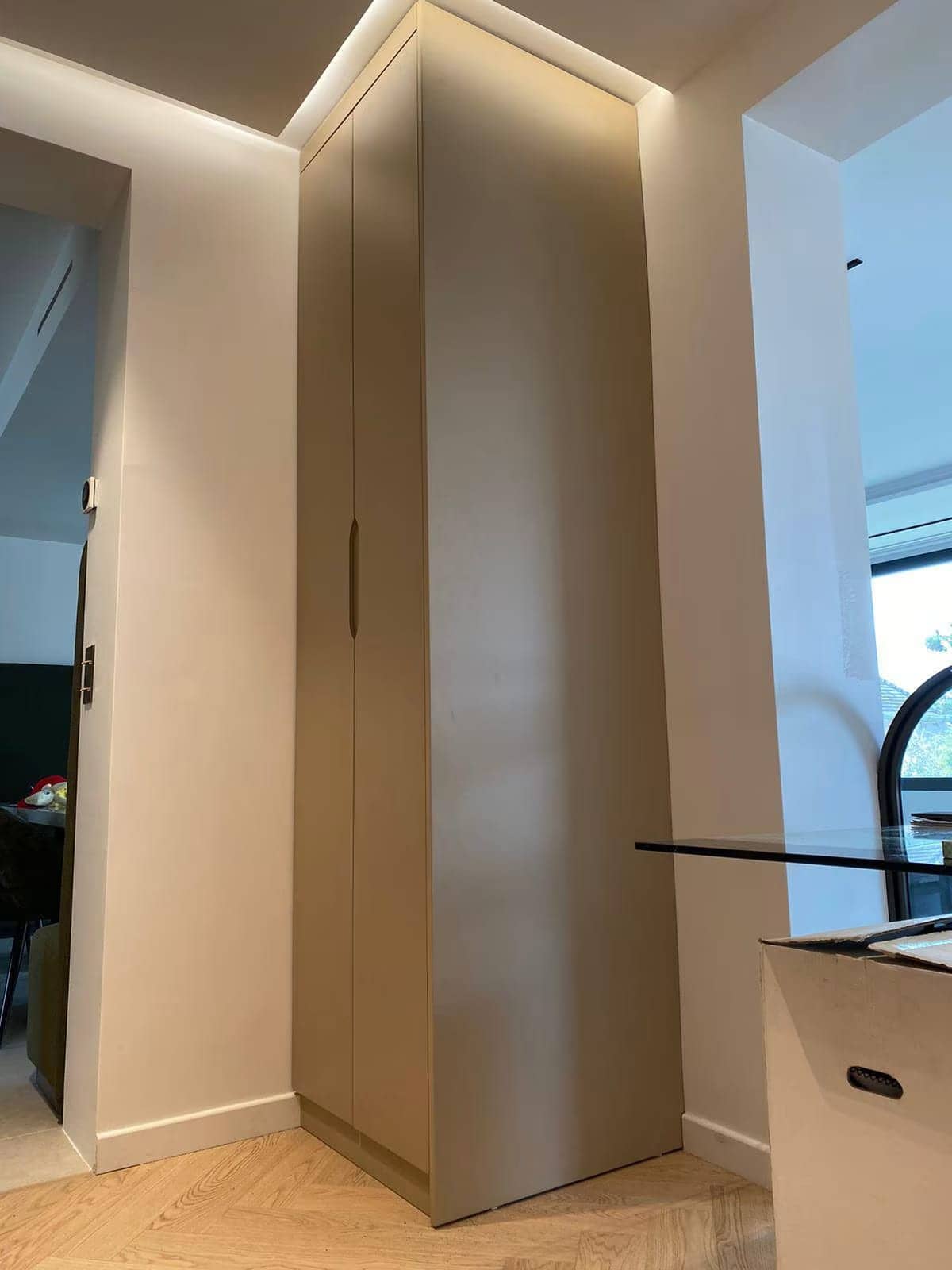 Placard d'angle haut beige à poignées creusées avec éclairage indirect au plafond