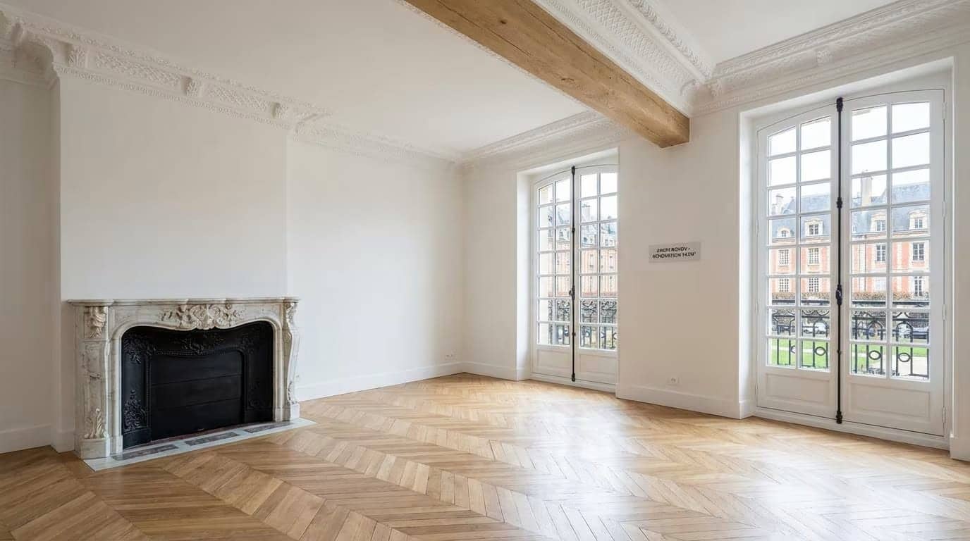 Salon haussmannien vide avec cheminée en marbre, poutre apparente et parquet en point de Hongrie à Paris