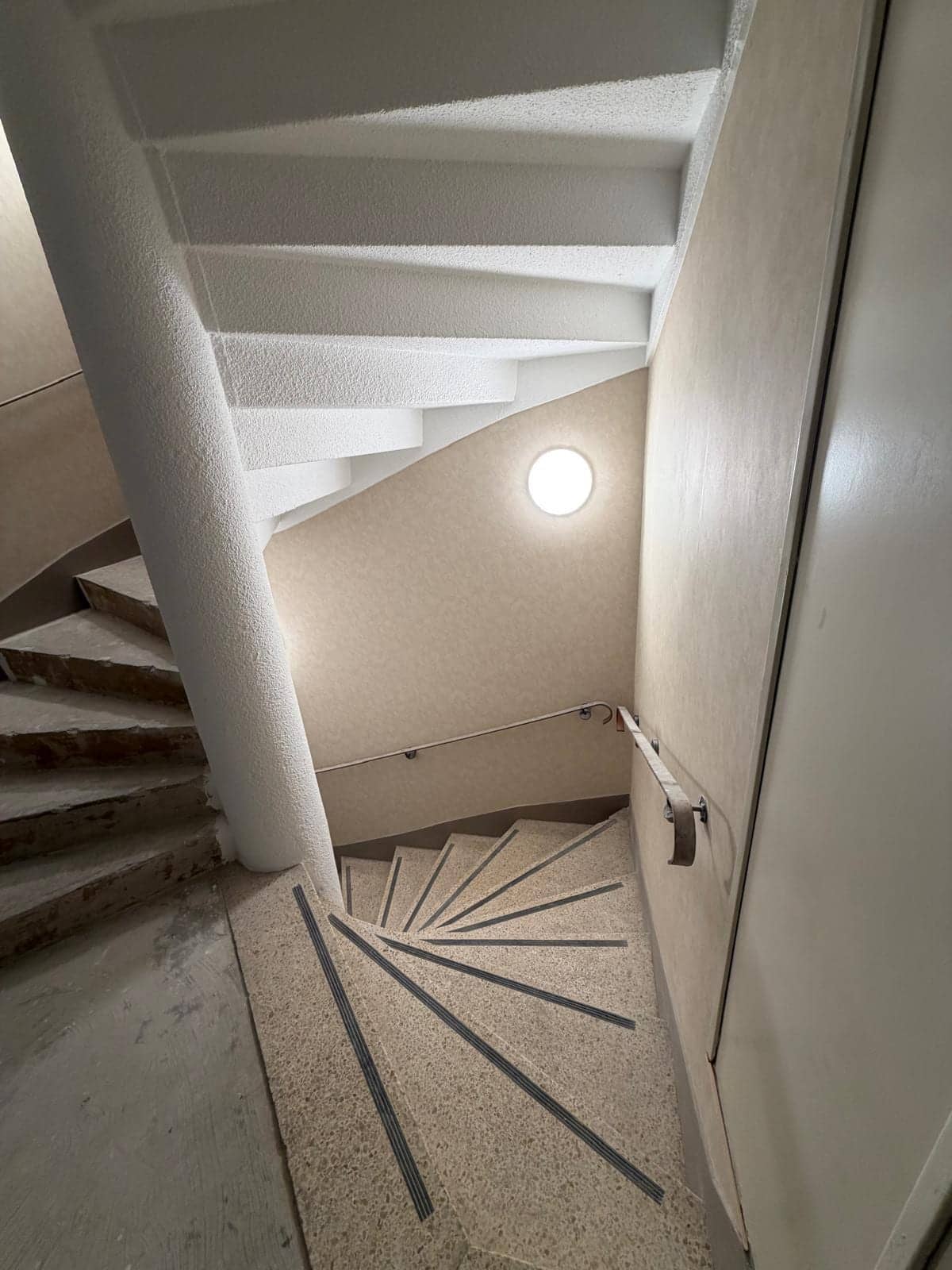 Escalier en colimaçon de parties communes rénové avec mur clair et sol en terrazzo à Vincennes