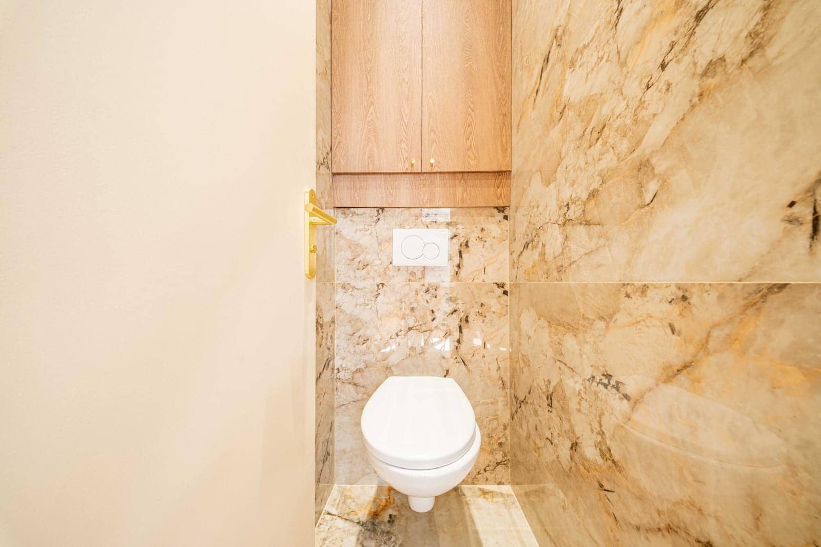 WC suspendu blanc entouré de marbre veiné et placard en bois clair, joints époxy